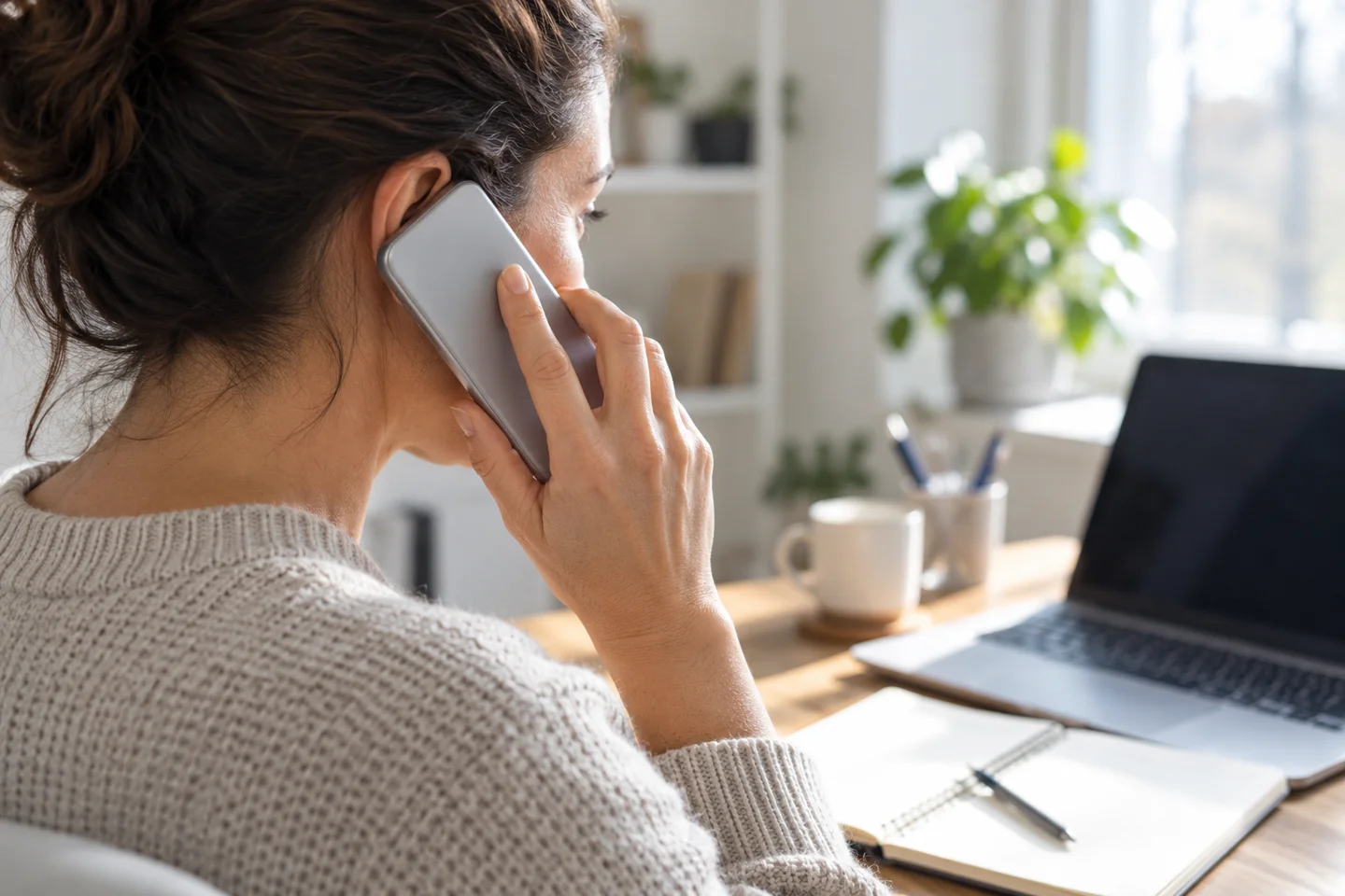 Person holding a phone to the ear beside a laptop